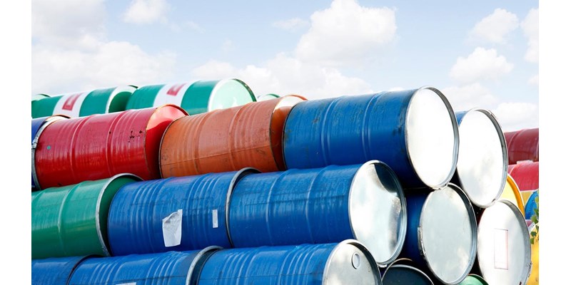 Stacked rows of red, green, blue and yellow oil drums.