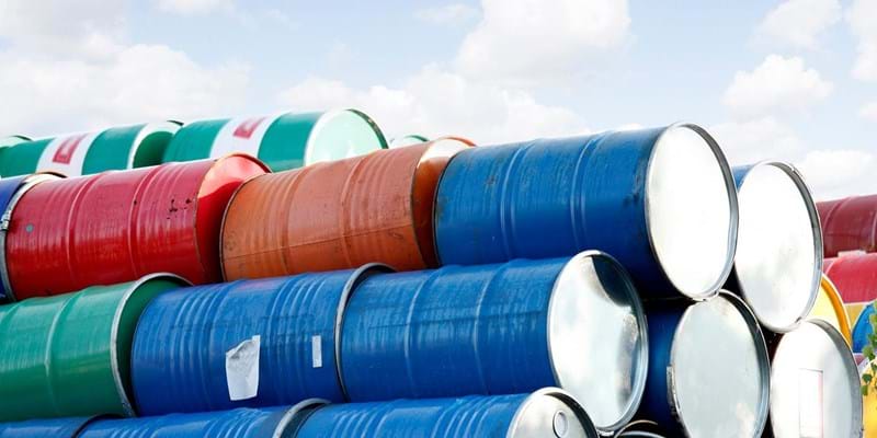 Stacked rows of red, green, blue and yellow oil drums.
