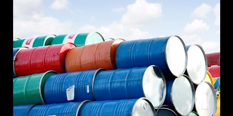 Stacked rows of red, green, blue and yellow oil drums.
