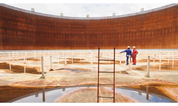 Technicians examining the interior of an empty fuel storage tank.
