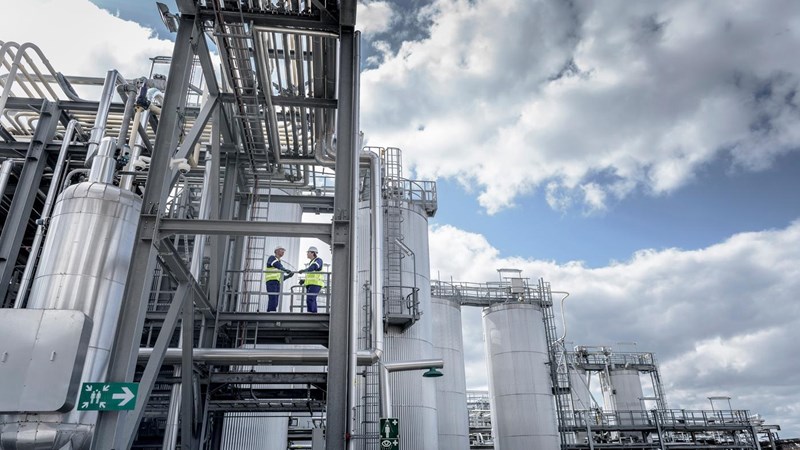 Two workers standing on the exterior steps of an industrial plant.
