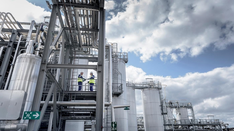 Two workers standing on the exterior steps of an industrial plant.