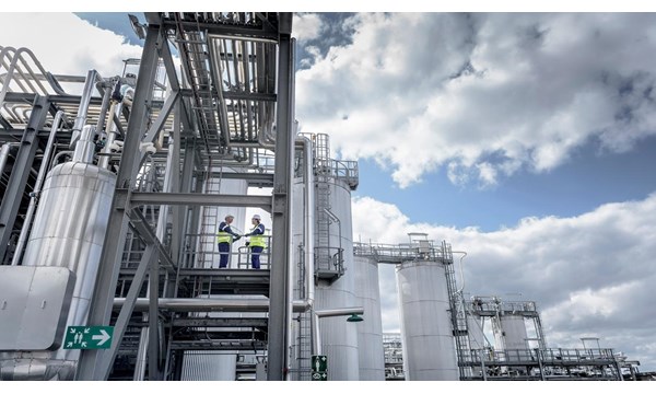 Two workers standing on the exterior steps of an industrial plant.