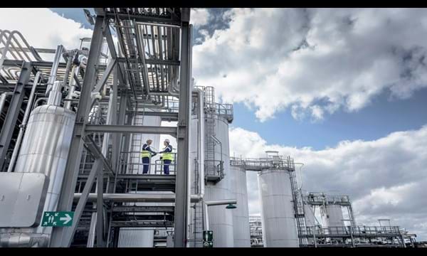 Two workers standing on the exterior steps of an industrial plant.