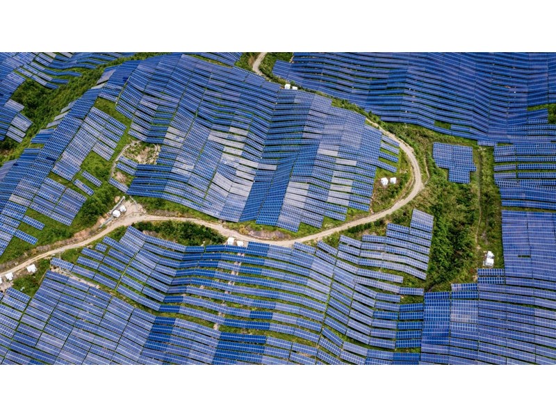 An aerial view of a countryside/hilltop solar farm.