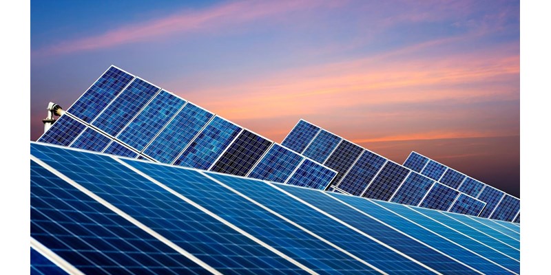 A close-up of two rows of solar panels at dusk.