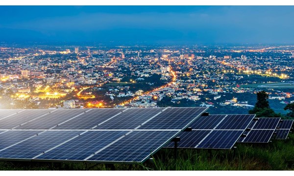 Solar panels on top of a hill overlooking an illuminated city at night.