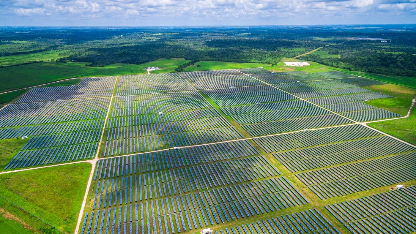 An aerial view of a vast solar farm spread across the countryside.