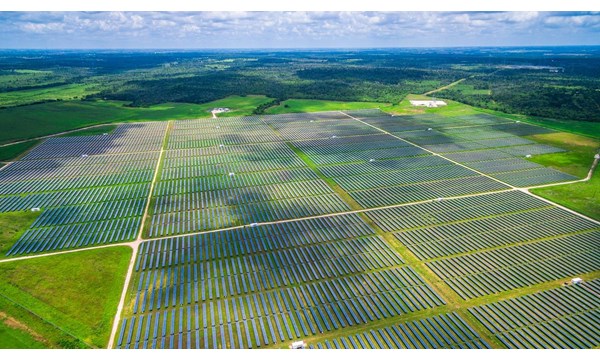 An aerial view of a vast solar farm spread across the countryside.