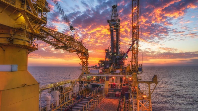 A view from aboard an oil rig in the ocean at sunset.