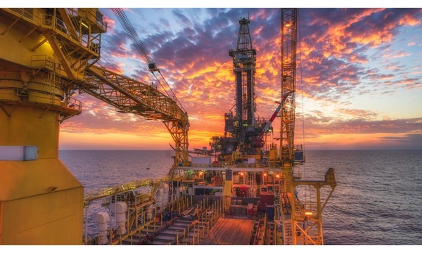A view from aboard an oil rig in the ocean at sunset.
