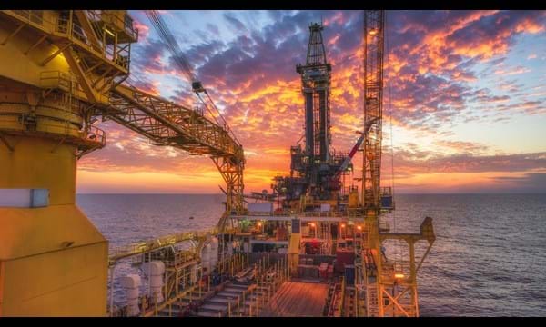 A view from aboard an oil rig in the ocean at sunset.