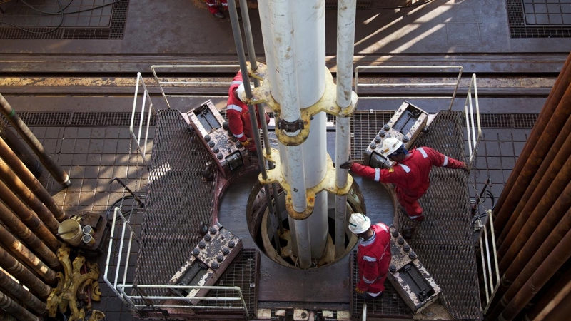 Aerial shot of engineers working a drill, atop an oil rig.