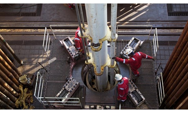 Aerial shot of engineers working a drill, atop an oil rig.
