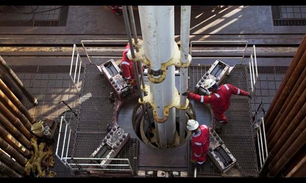 Aerial shot of engineers working a drill, atop an oil rig.