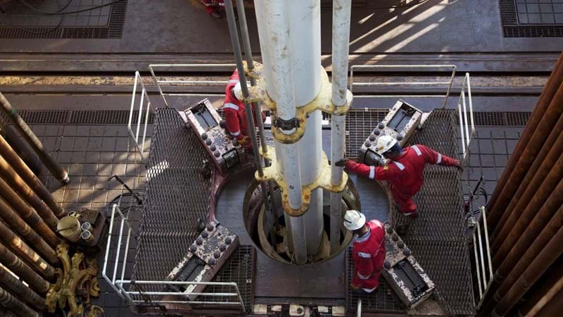 Aerial shot of engineers working a drill, atop an oil rig.