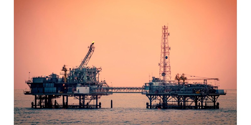 A close-up of two connected sections of an oil rig at sunset.