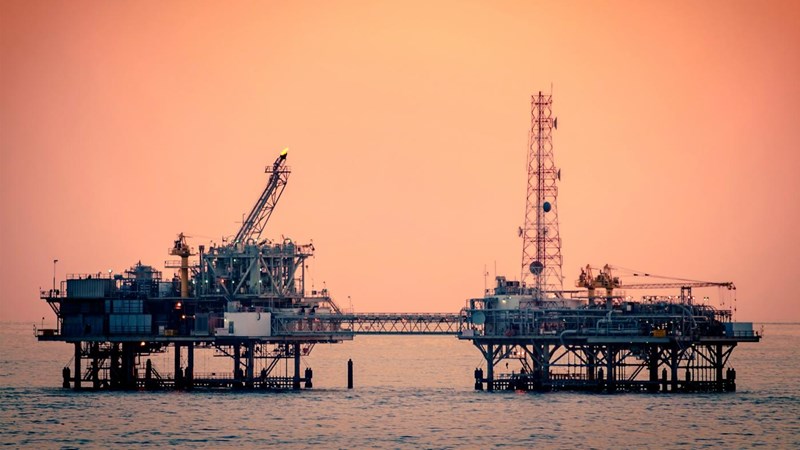 A close-up of two connected sections of an oil rig at sunset.