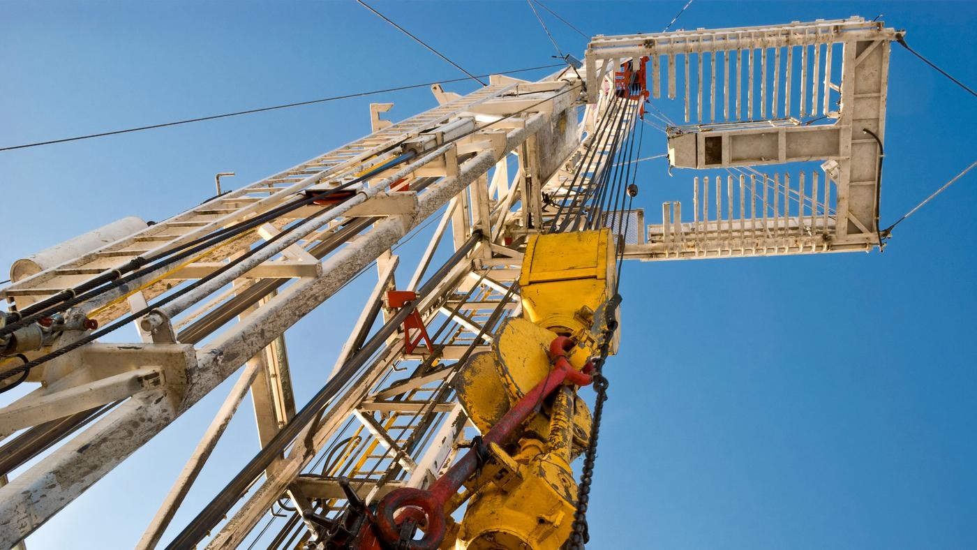 Upward view of a drilling section of an oil rig, blue sky in the background.
