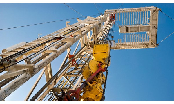 Upward view of a drilling section of an oil rig, blue sky in the background.