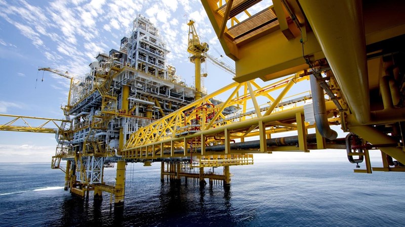 A close-up of a yellow and white oil platform in the middle of the ocean.