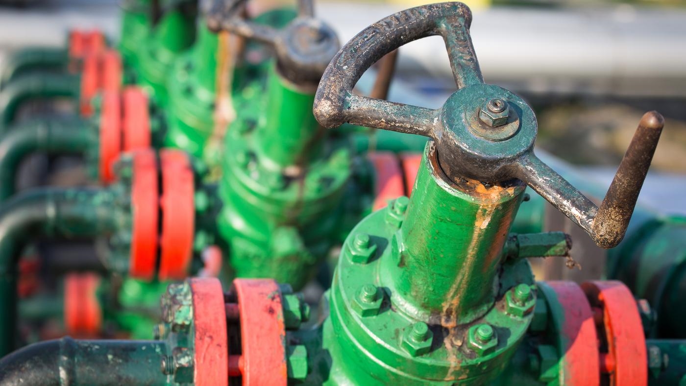 A group of green and red valves on a pipeline.