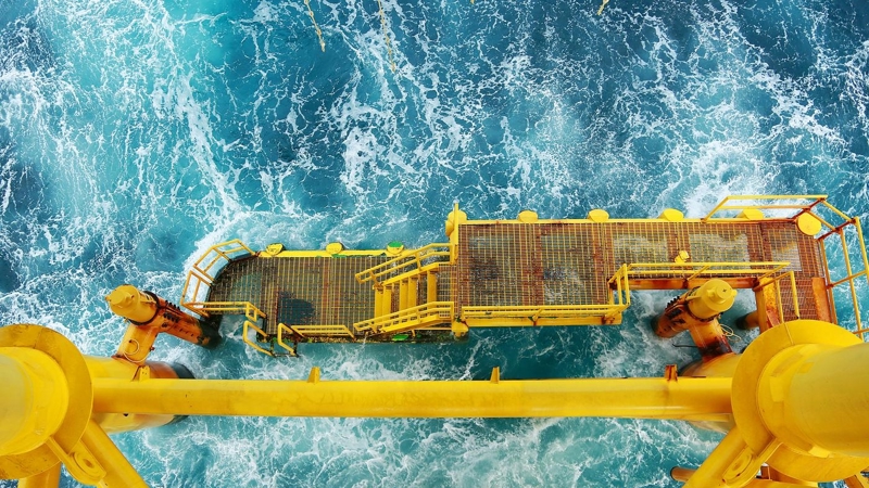 An aerial view of an oil rigs platform and pipes, are drilling into the ocean.