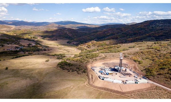 An aerial view of a drilling rig in the mountains.