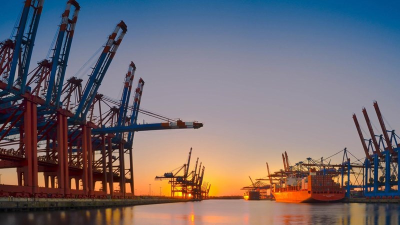 A ship docked in a port at sunset.