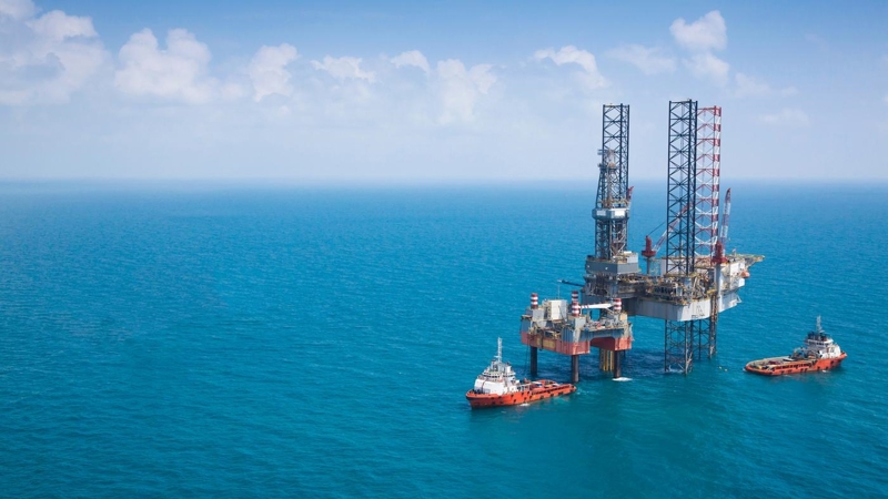 Two oil rigs and vessels in the middle of the ocean.