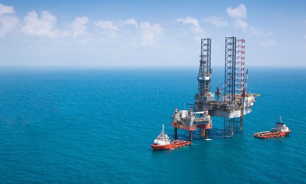 Two oil rigs and vessels in the middle of the ocean.