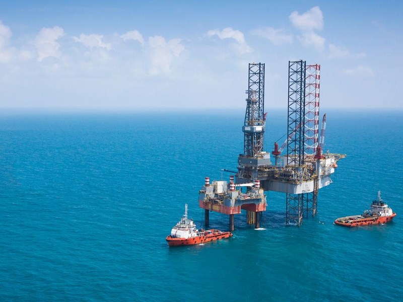 Two oil rigs and vessels in the middle of the ocean.