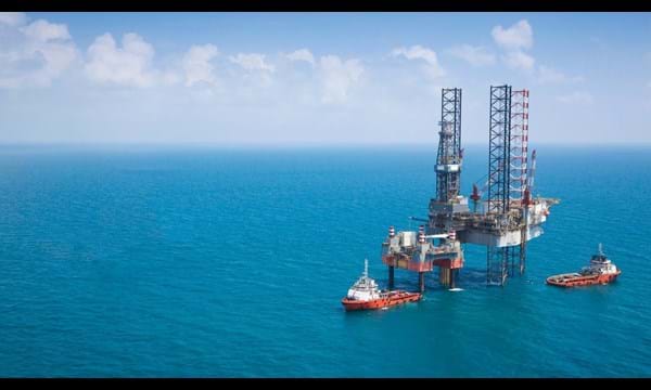 Two oil rigs and vessels in the middle of the ocean.