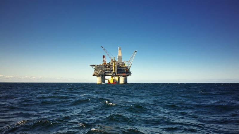 An oil rig in the middle of an open choppy sea.