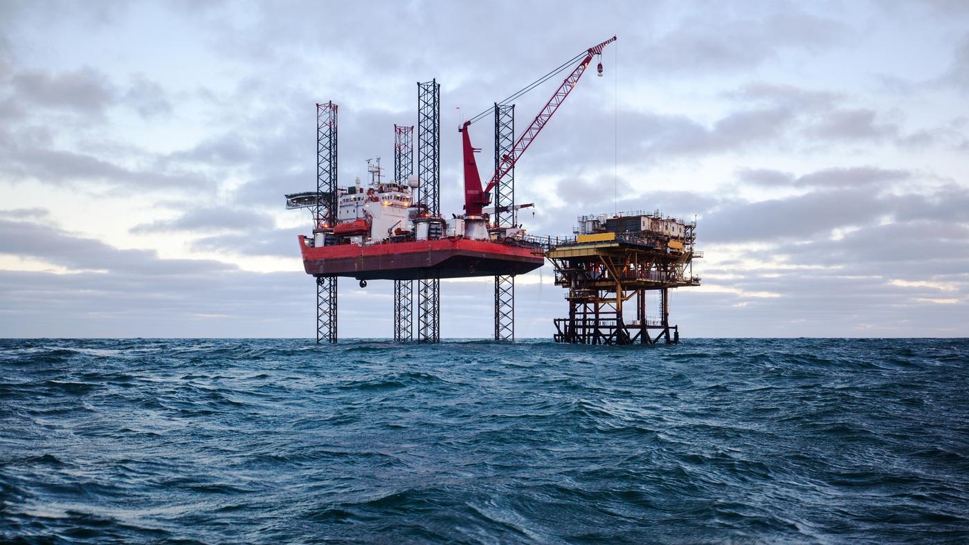 Two oil drilling rigs in open choppy waters.