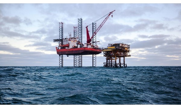 Two oil drilling rigs in open choppy waters.