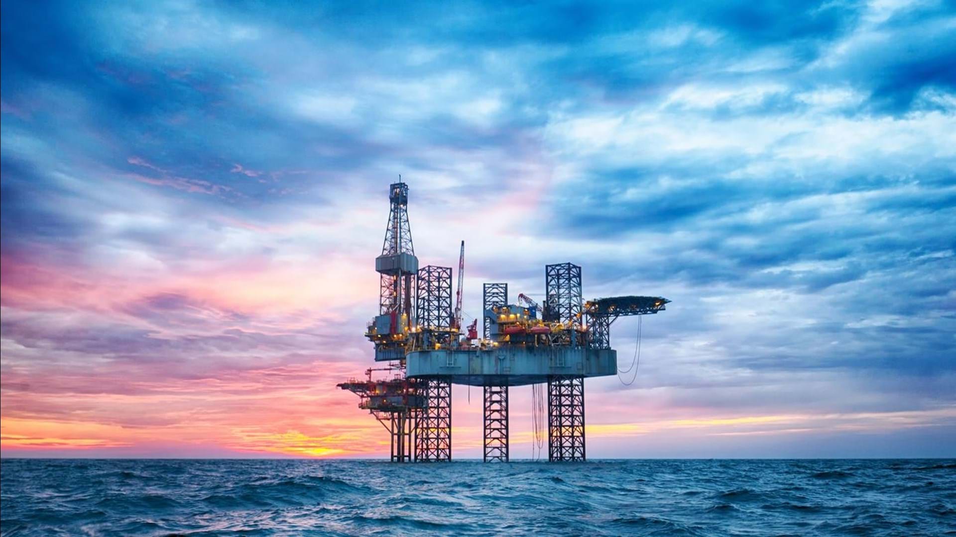 A close-up of an oil rig in open choppy waters, during sunset.