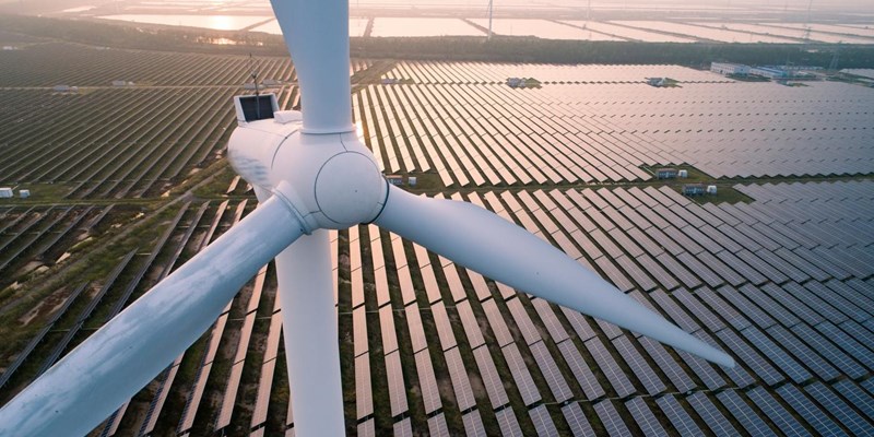 An aerial view of a wind turbine in a solar field.