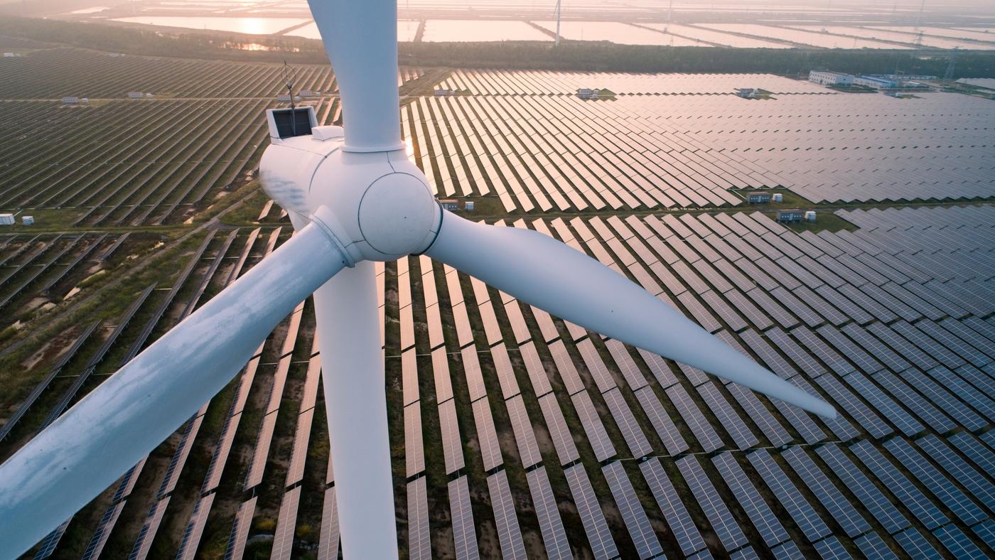 An aerial view of a wind turbine in a solar field.