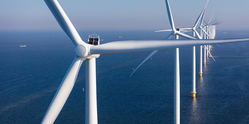 A close-up of a row of wind turbines in the open sea,