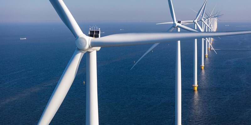 A close-up of a row of wind turbines in the open sea,
