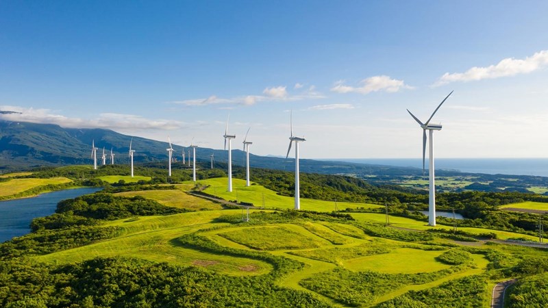 A row of wind turbines in the mountain coastal cliffs, under the blue sky.