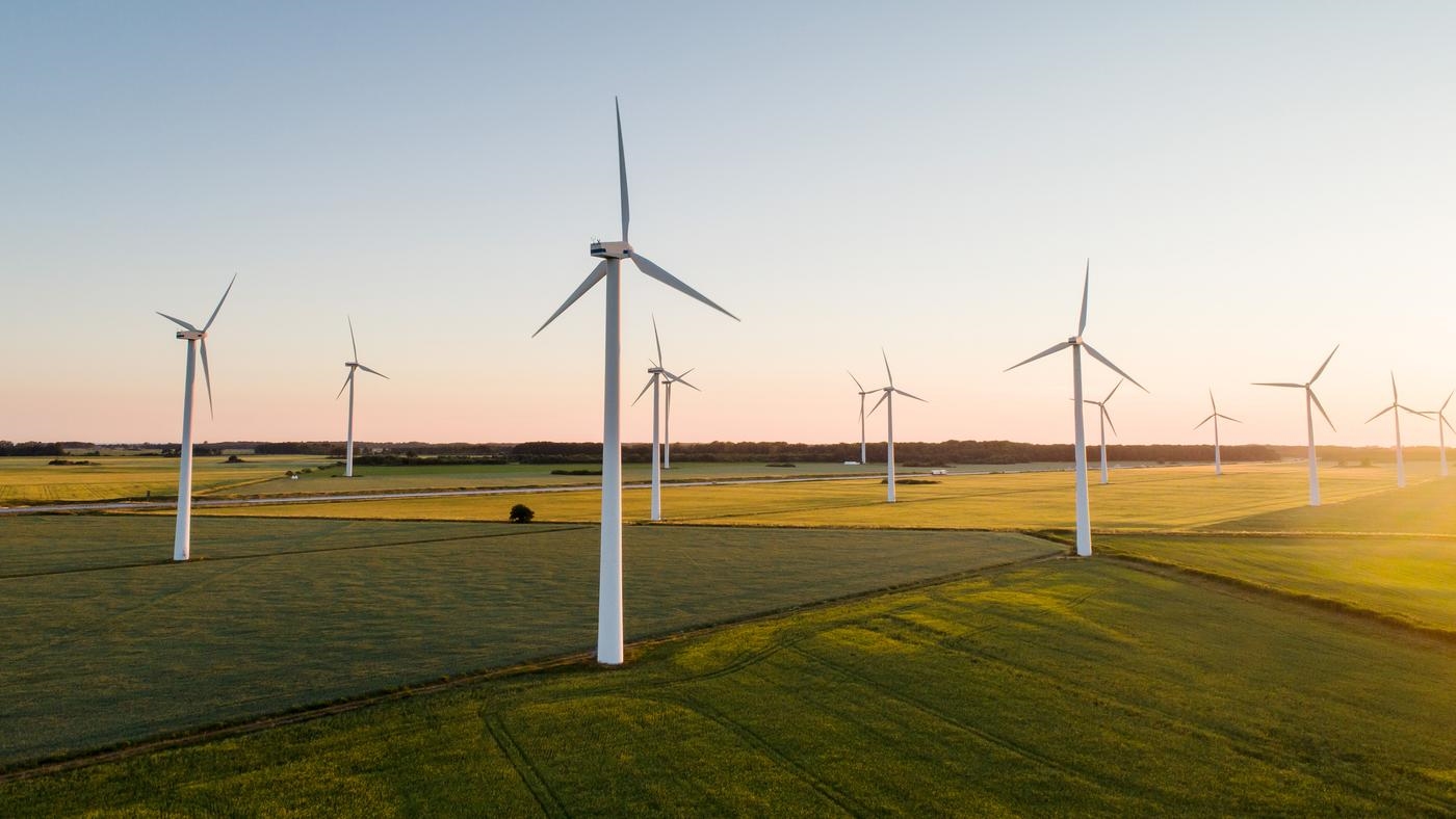 Wind farm in the middle of countryside fields at dusk.