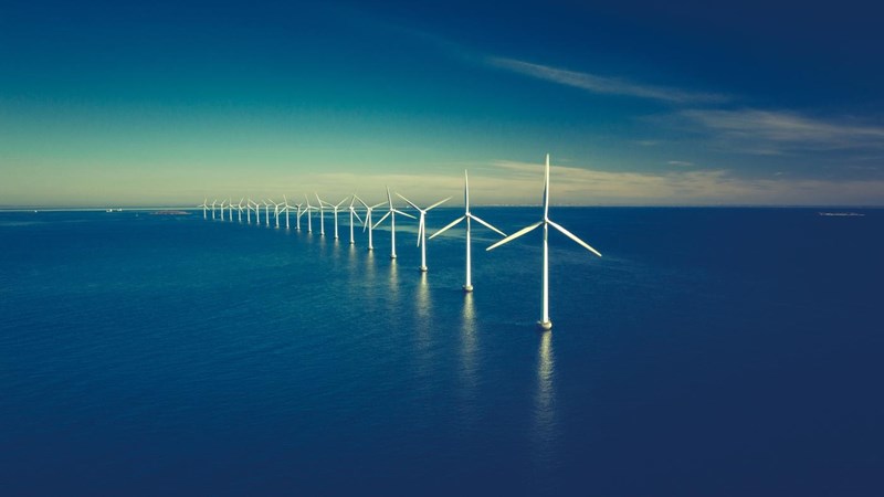 A row of wind turbines at sea.