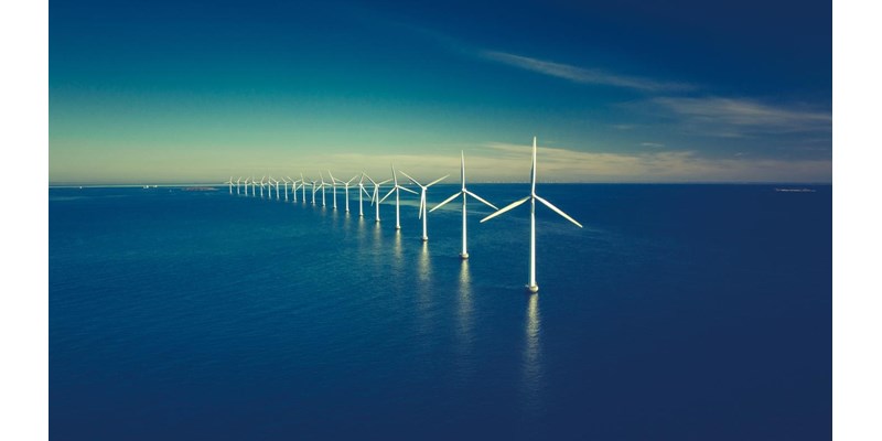 A row of wind turbines at sea.
