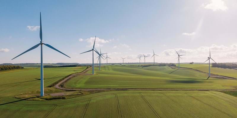 Aerial view of wind turbines in a field, on a sunny day.