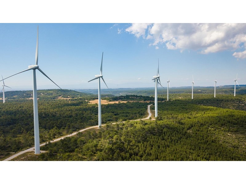 Wind turbines placed along a winding country road.