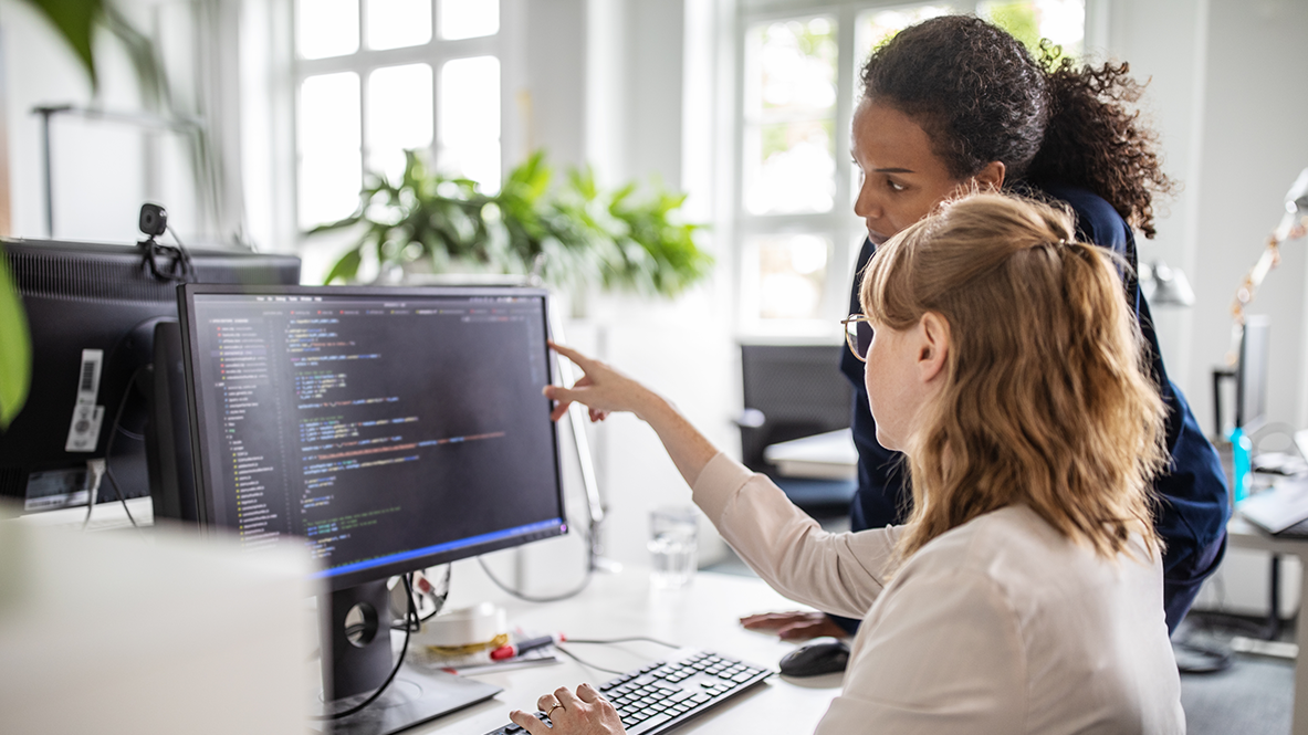 Two SRE team members reading computer screen.